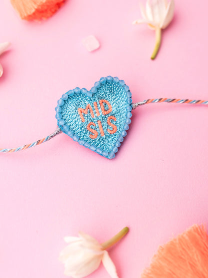 Decorative sister rakhi with heart-shaped mid sis text