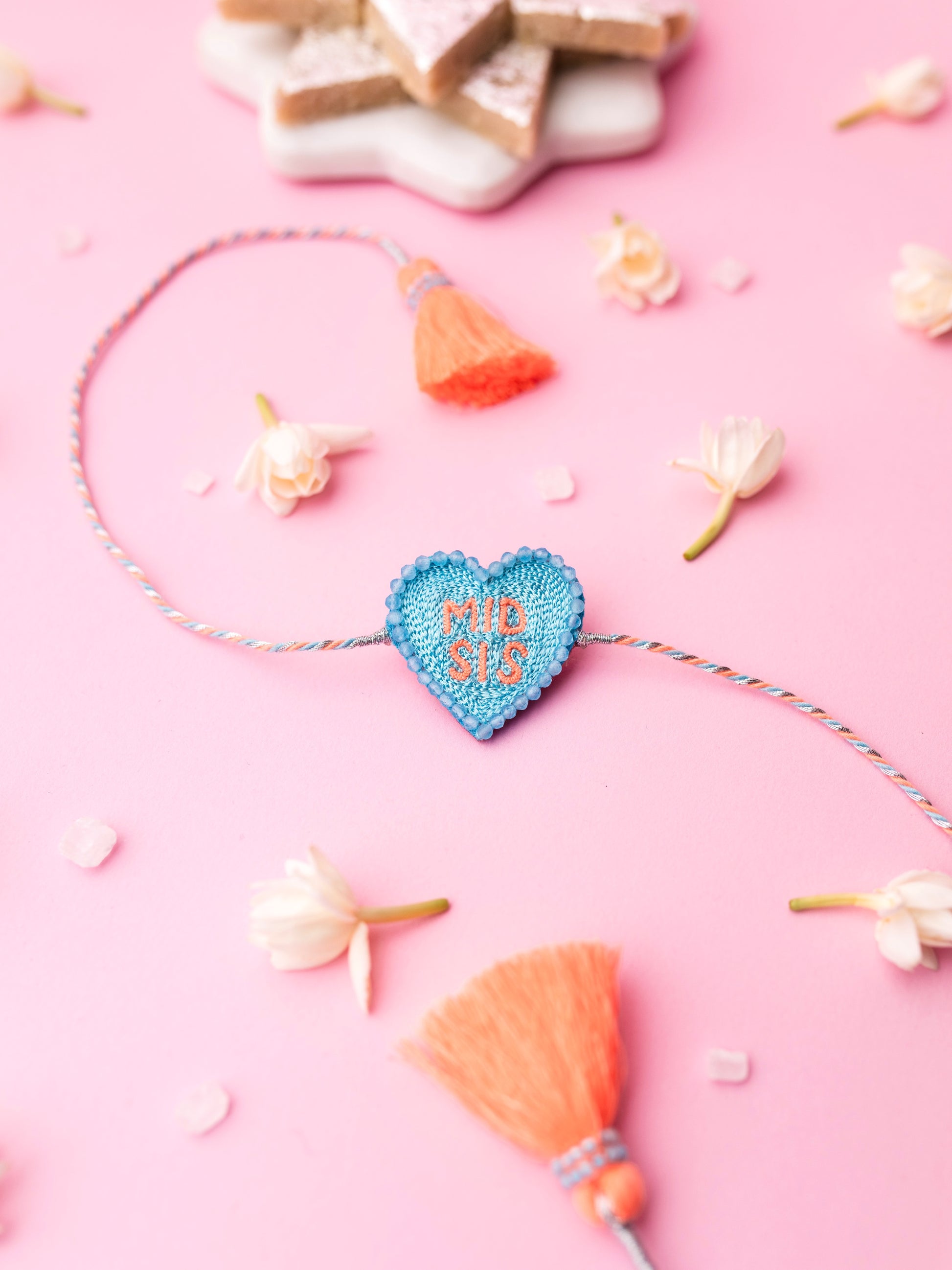Decorative sister rakhi with heart-shaped mid sis text