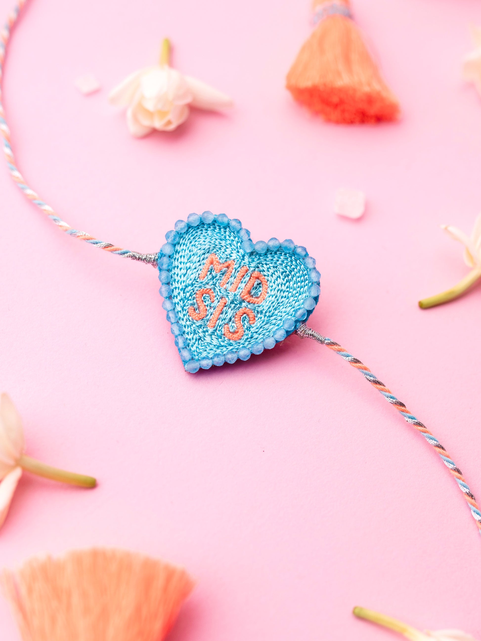 Decorative sister rakhi with heart-shaped mid sis text