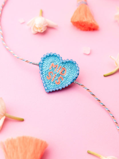 Decorative sister rakhi with heart-shaped mid sis text